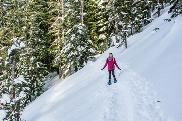 Winter sport activity. Adventurous woman snowshoeing through the forest in deep snow.