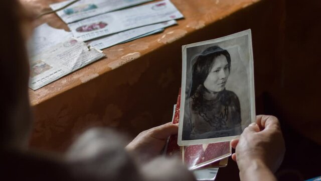 Elderly woman sitting in armchair and browsing old photos