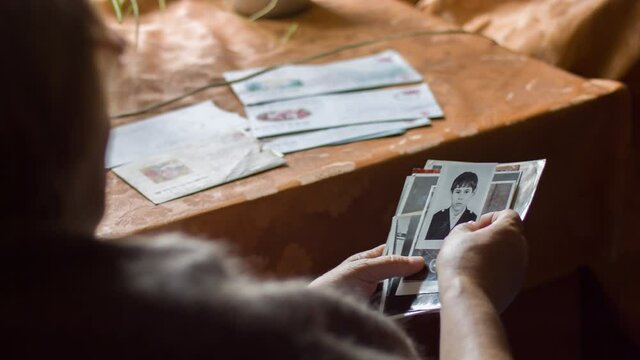 Elderly woman sitting in armchair and browsing old photos