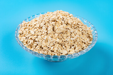 side view glass bowl of oatmeal on blue background