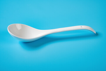 side view ceramic soup spoon on a blue background