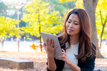 Fototapeta premium 【東京都】屋外でタブレットを操作する女性【2020年 紅葉】