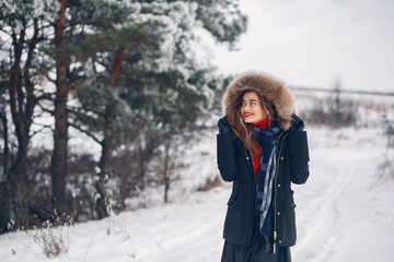 Fototapeta na wymiar Cute girl walking in a winter park. Woman have fun with snow.