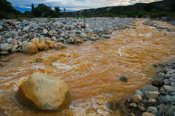 Unique yellow river called River of Gold due to the presence of iron, flowing along the rocky valley in La Rioja, Argentina.
