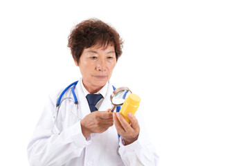 Chinese old doctor is looking at medicine bottle with magnifying glass in front of white background