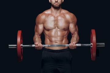 Close up of strong bodybuilder muscular arms lifting a barbell isolated on black background