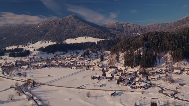 Panoramic drone video of a small alpine village at winter covered with snow