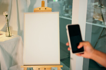 Artist taking picture of empty canvas with smartphone.
