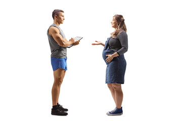 Fototapeta premium Full length profile shot of a pregnant woman talking to a fitness instructor