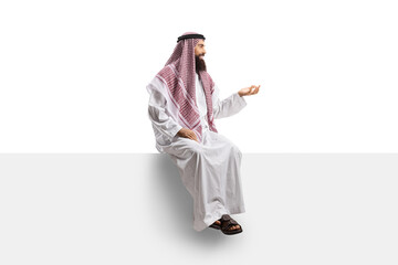Saudi arab man sitting on a panel and gesturing with hand