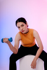 Sporty asian woman sitting on chair and holding dumbbell.