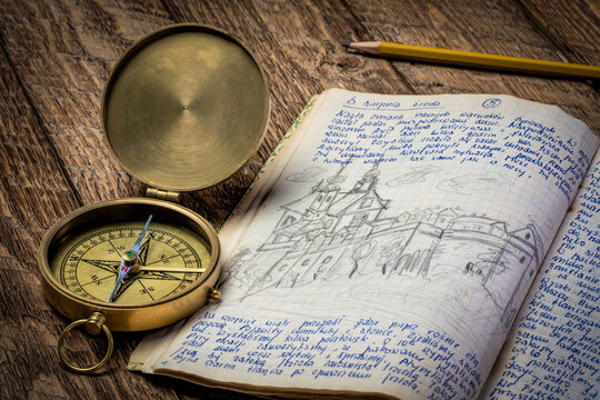 Vintage travel journal with handwriting and pencil sketches (property release attached) and old brass compass.