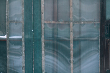 The wall of an abandoned house. Old window covered with plastic