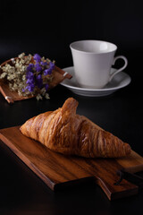 Croissant on a wooden cutting board on a black background