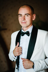 Man in a suit and bow-tie. Morning preparation groom at home. Fashion photo of a man.