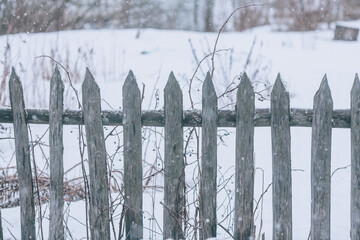 Old wooden fence in the village in winter