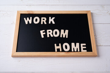 `Work from Home` words on a modern board on a white wooden surface, top view. Overhead, from above, flat lay.
