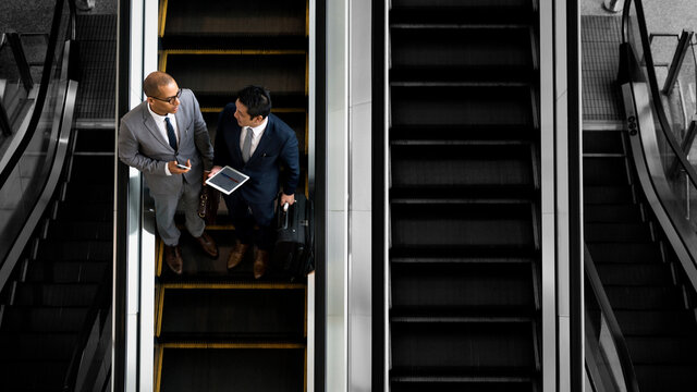 Business people discussing on an escalator - Powered by Adobe