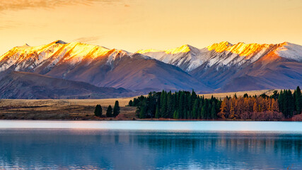 The last sunshine and rays  of the day lighting up the snow covered mountain peaks at Lake Tekapo