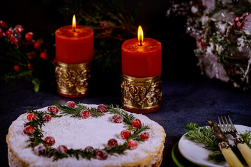 Festive holiday pie with cranbarry decoration on black table with burning candles.