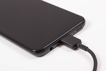 Plug of charger connected to mobile phone. Smartphone charging