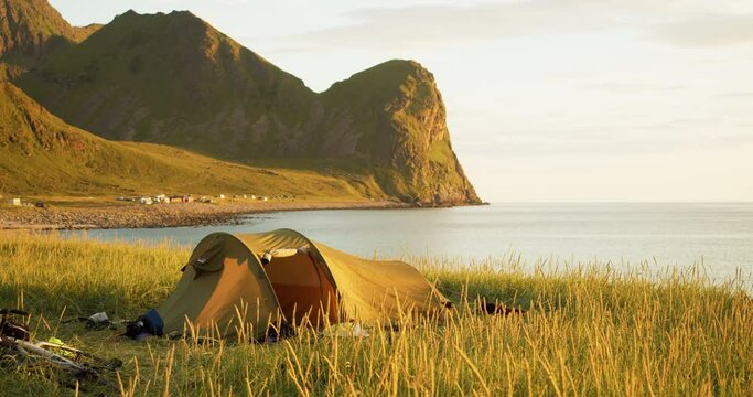 Abandoned tent on Lofoten coast with mountains glowing in midnight sun