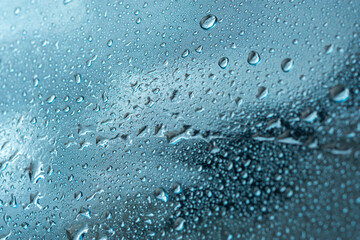 Abstract background with raindrops and beautiful blue bokeh. The concept of autumn and the cold stormy weather. Texture of macro drops on the blurred background of the window. Loneliness sadness