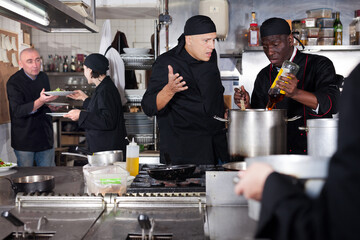 Positive cooks in process of working in kitchen of restaurant. High quality photo