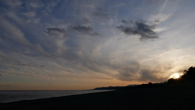 海岸の上を美しい夕焼け雲が流れていく風景（タイムラプス、インターバル撮影）（三重県七里御浜海岸）