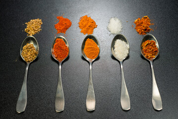 Random Spices in Spoon and out of spoon on floor on black background Indian and Pakistani Spices