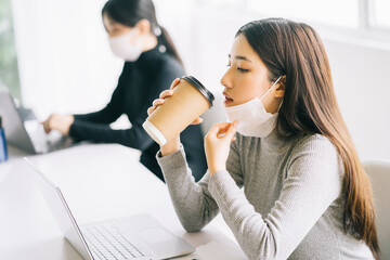 woman takes off mask to drink water
