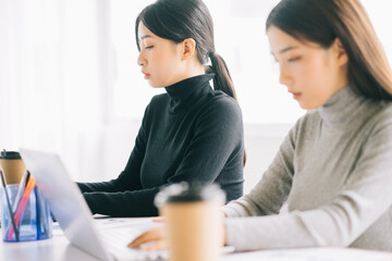 two asian business women are gathered in the office
