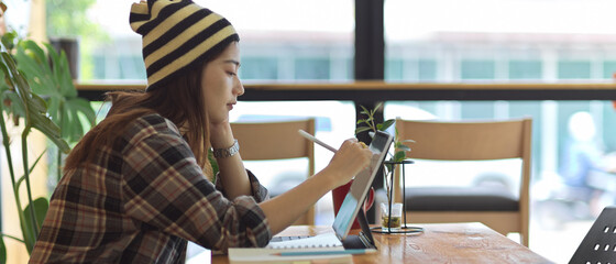 Female teenager working with digital tablet on wooden table