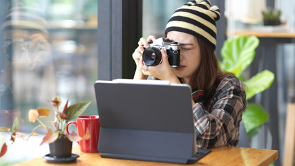 Naklejka premium Female teenager taking photo with digital camera while relaxed sitting in cafe