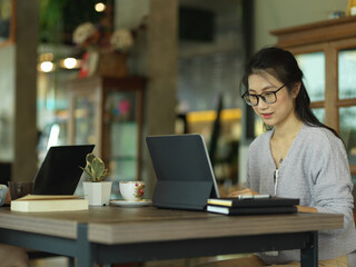 Side view of female freelancer working with digital tablet and stationery
