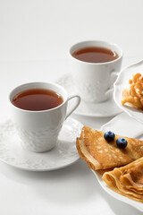 Close up view of dessert plate and china cups on white background