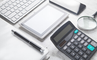 Computer keyboard, tablet, smartphone, pen, calculator, document on the desk.