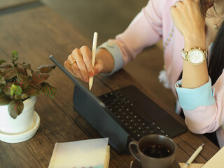 Female freelancer working with digital tablet on wooden table in cafe