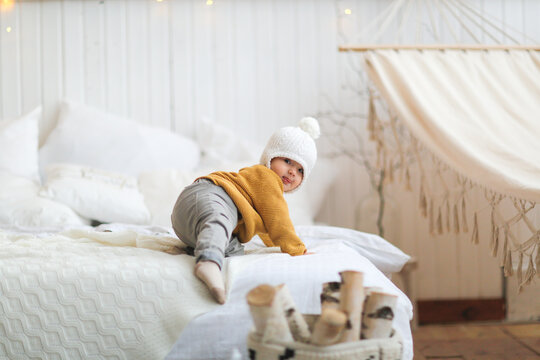 cozy caucasian christmas child by the bed in a light interior, home photos of children, concept of new year and christmas