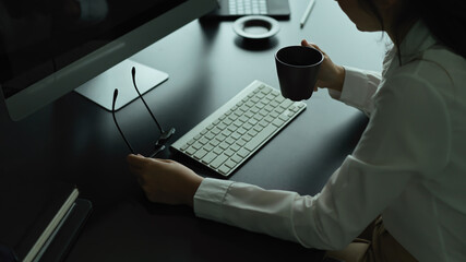Female hand holding eyeglasses and holding coffee cup on office desk