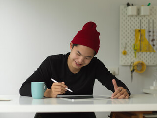 Male using digital tablet on white worktable in home office room