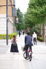 A businessman riding a sharing bicycle and waiting for a traffic light