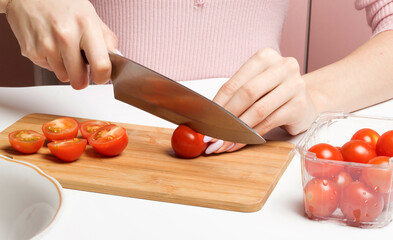 Slicing red cherry tomatoes on a wooden Board