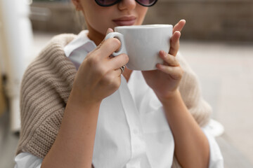 Beautiful girl in a street cafe drinks coffee