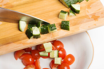 sliced fresh cucumbers are transferred to a salad bowl