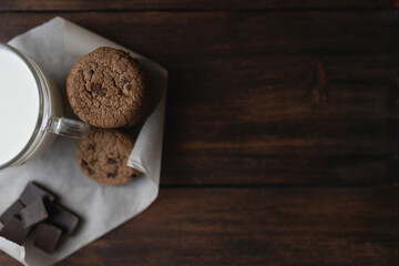 Plakat Oat cookies, pieces of chocolate and a glass of milk on a dark wooden background