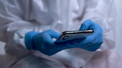 Nurse with EPI suit consulting mobile application on mobile phone