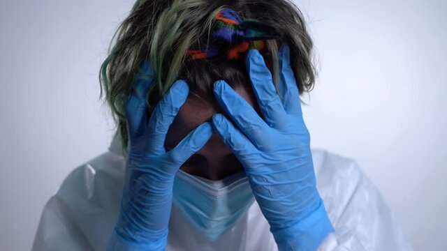 Nurse puts her hands on her face desperate for the coronavirus situation then stares at the camera