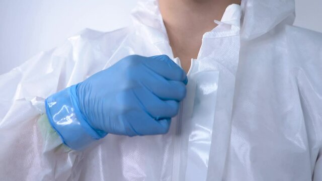 Young female doctor zipping up PPE suit, preparing to fight covid-19
