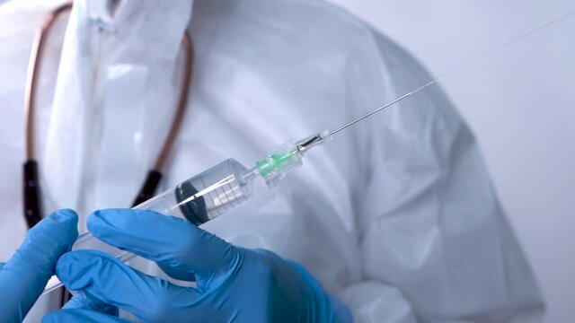 Doctor pressing syringe and releasing liquid from the tip